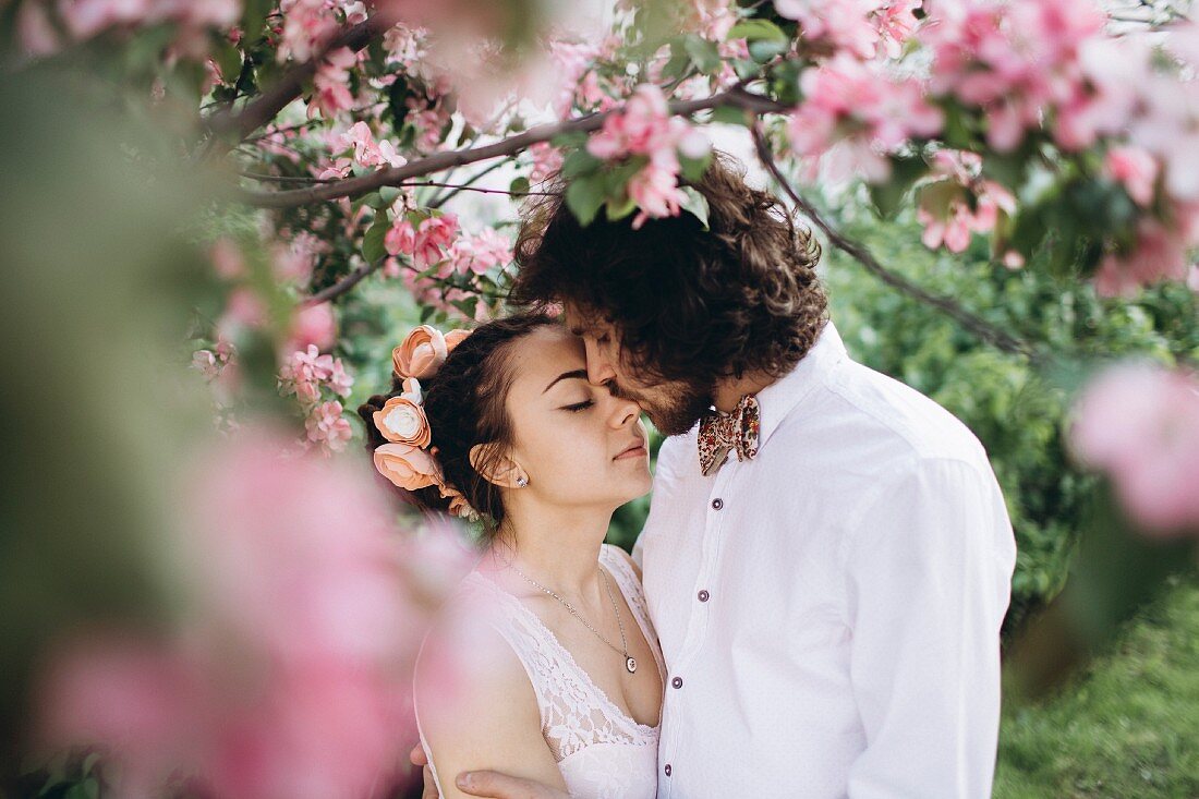 Brautpaar küsst sich unter blühendem Kirschbaum