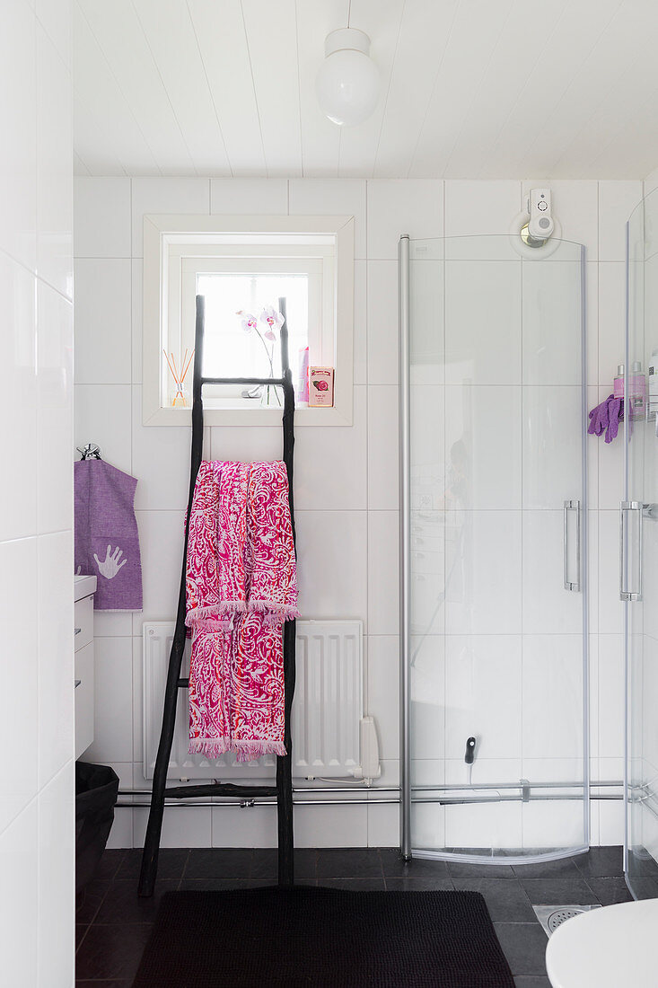 Shower stall and ladder used as towel rail in white bathroom