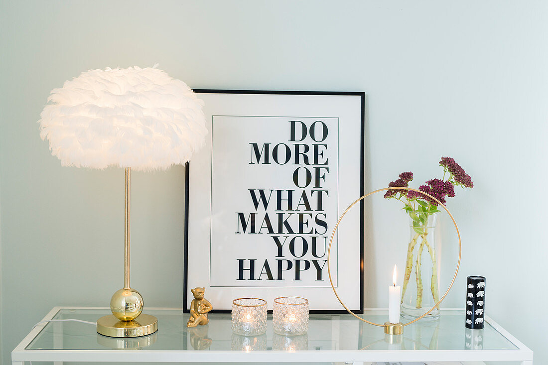 Table lamp, framed motto, vase and candlestick on sideboard with glass top