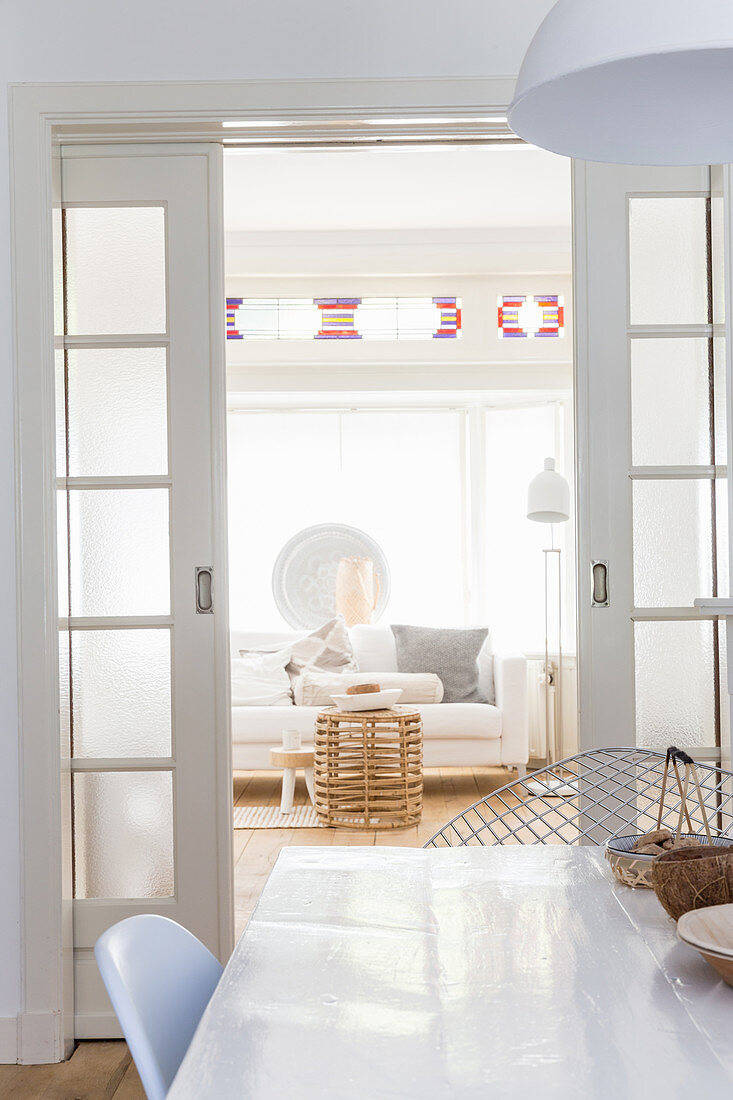Blick über Esstisch und durch geöffnete Schiebetür auf weiße Sofa im Wohnzimmer