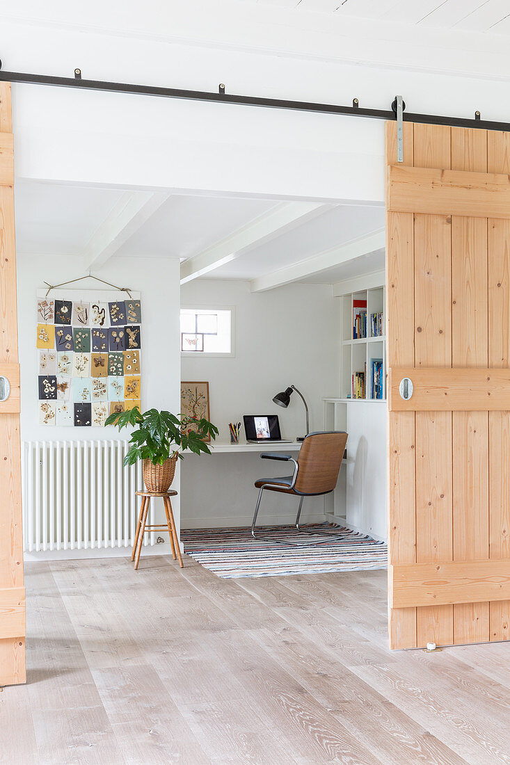 Barn-style sliding door leading into bright room with workspace