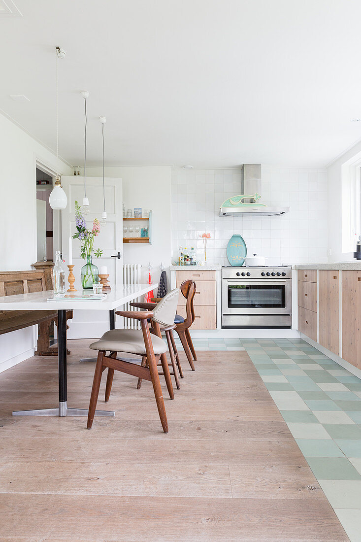 Retro chairs at dining table in kitchen with different floor coverings