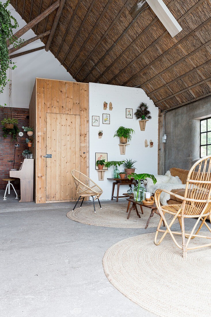 Wohnzimmer mit Korbmöbeln und Pflanzen in einer alten Scheune