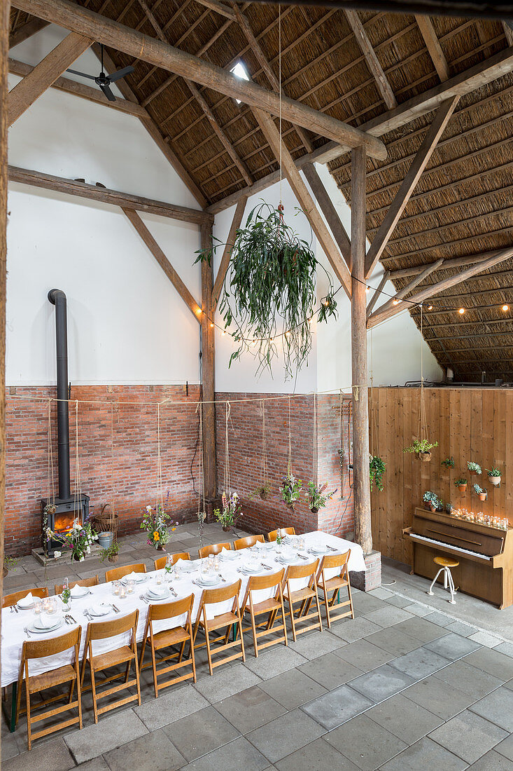 Flower arrangements suspended over set dining table in converted barn