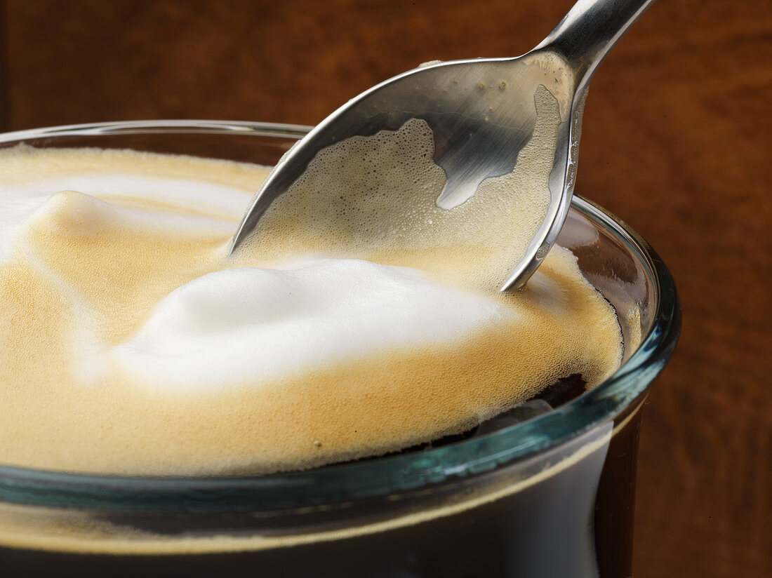 Milk foam on a coffee with a spoon
