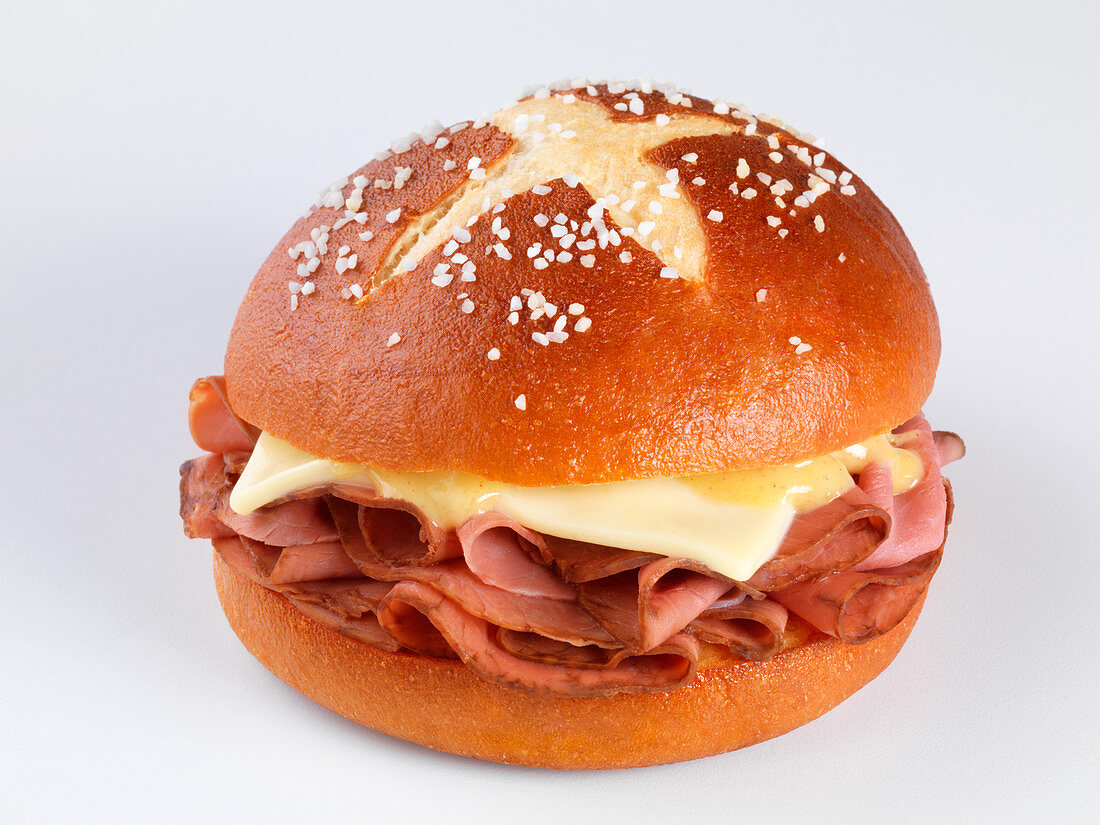 A pretzel roll filled with pastrami and cheese