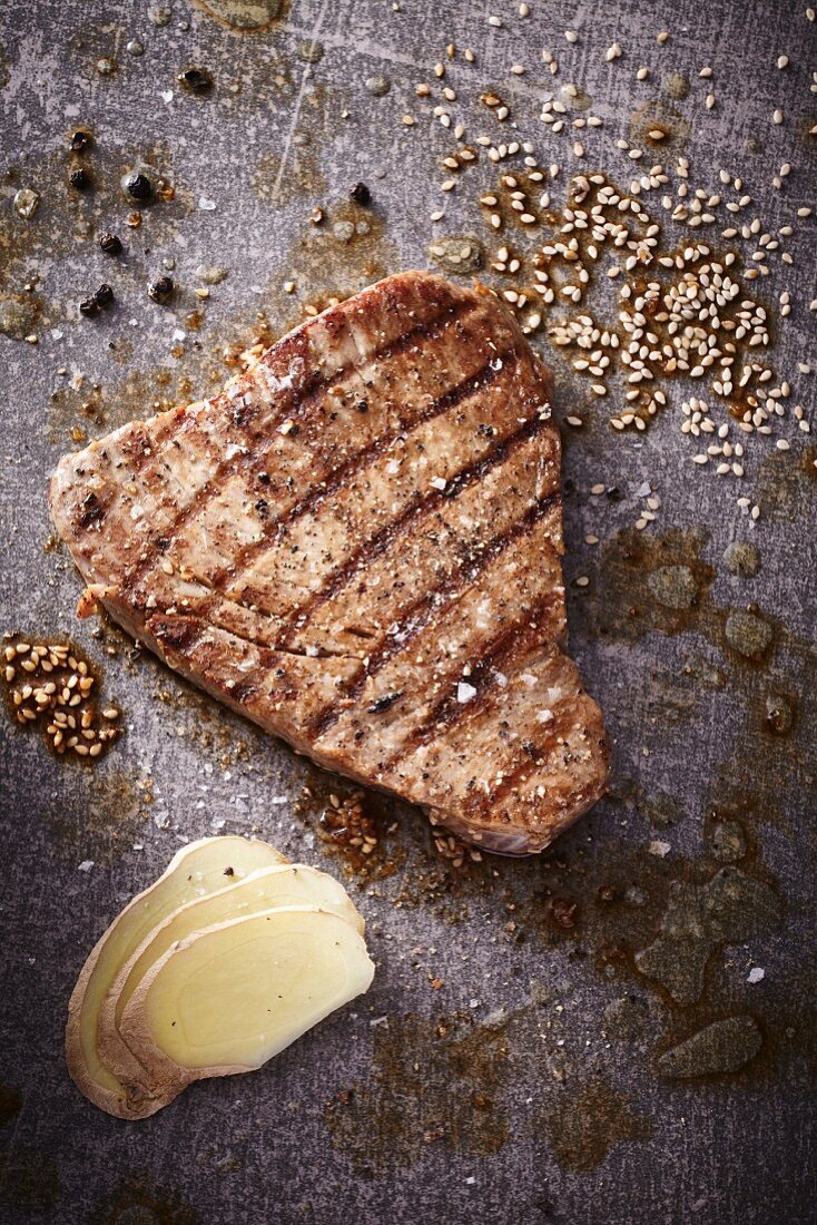 A grilled tuna steak with sesame seeds and slices of ginger
