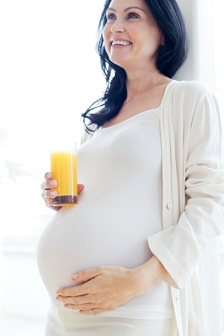 Pregnant woman touching tummy with juice