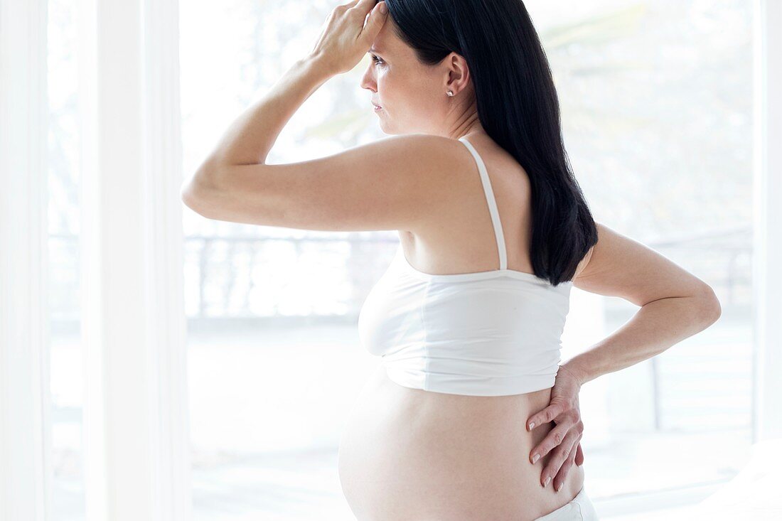 Pregnant woman rubbing back with hand on head