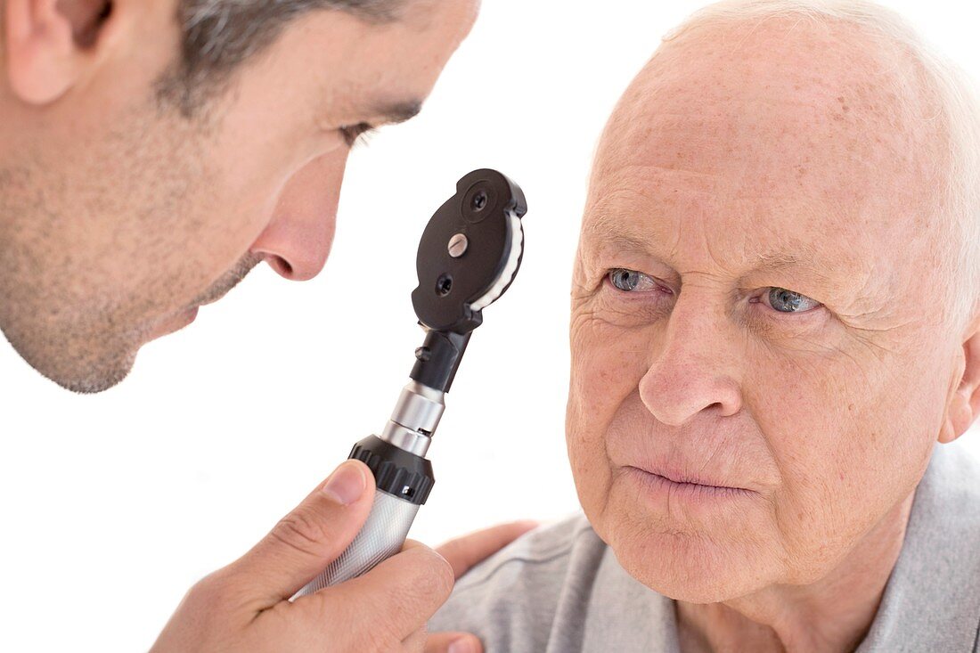 Male doctor examining senior patient's eye