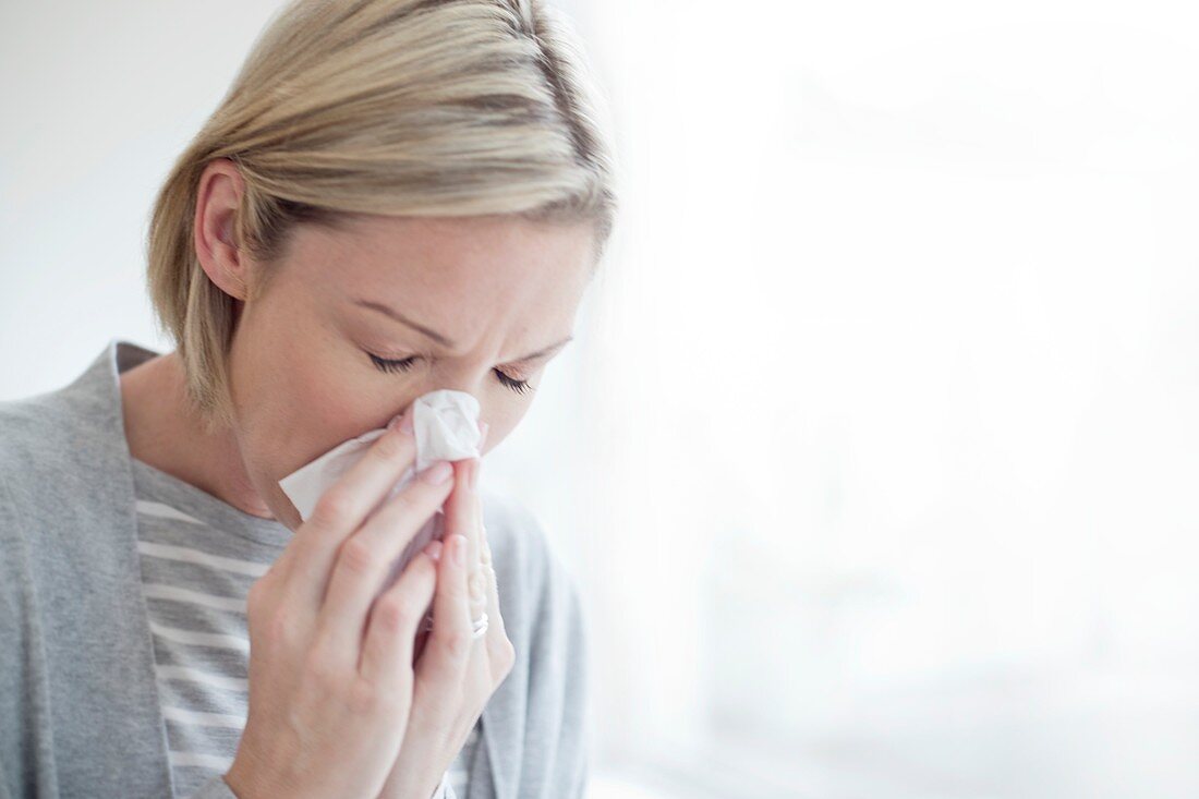 Mid adult woman blowing her nose