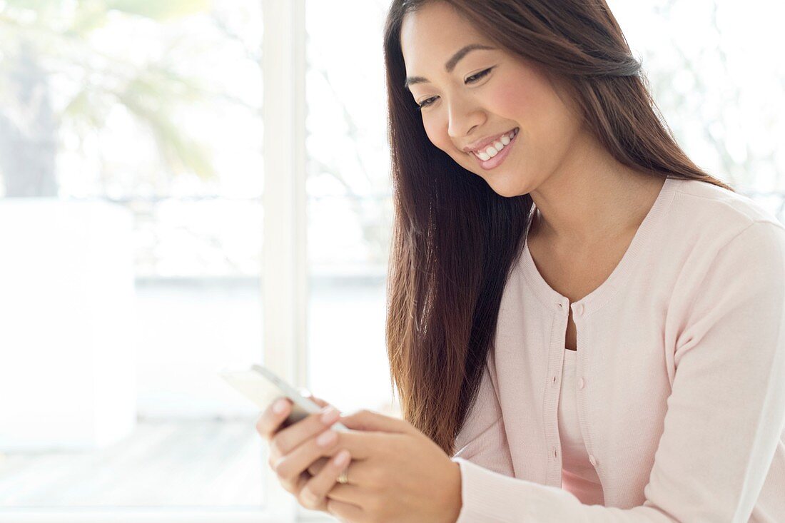 Woman using smartphone, smiling