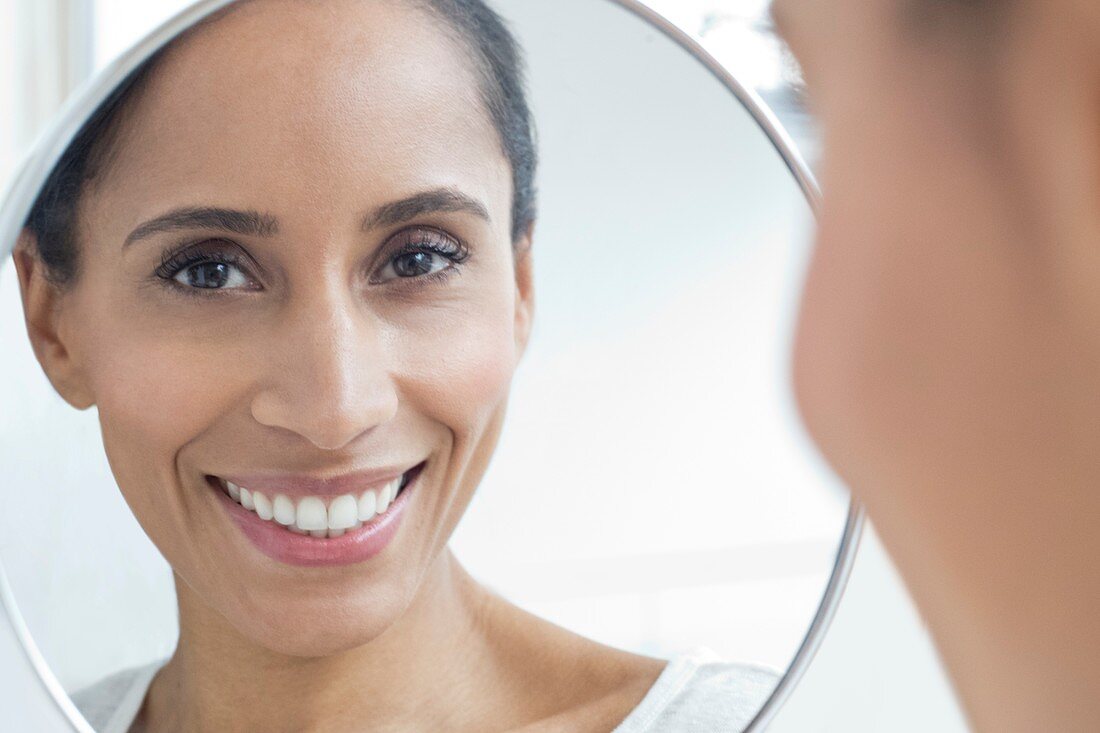 Woman looking in mirror, smiling