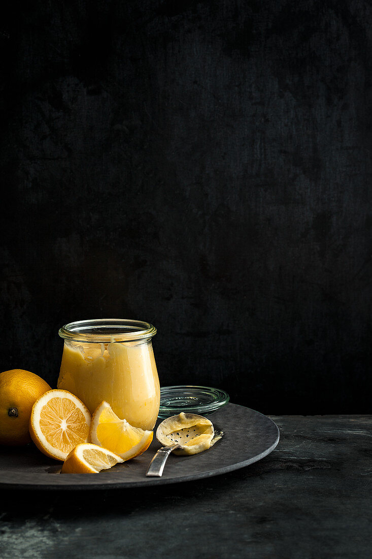 Lemon Curd im Glas auf schwarzem Teller