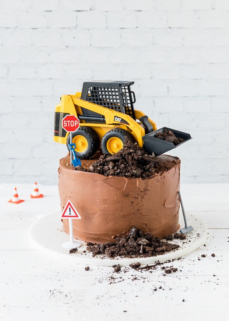A chocolate cake topped with a digger and building site decorations