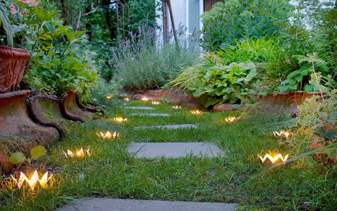 Crown-shaped candle lanterns hand-made from tin cans lining garden path