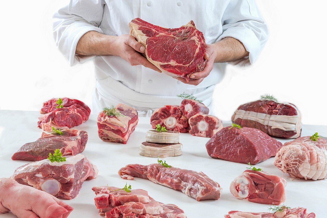 A chef presenting different types of fresh raw meat