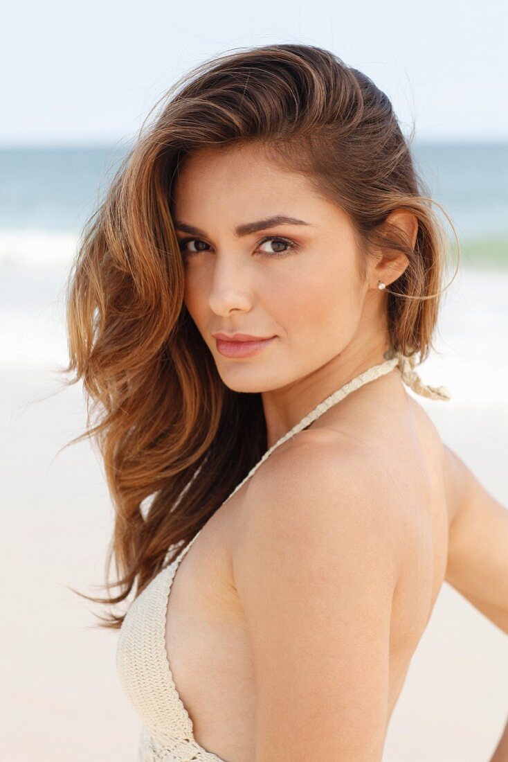 A young woman on a beach wearing a crocheted bikini top