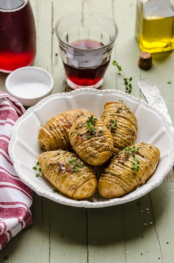 Hasselback potatoes with olive oil and thyme, served with a glass of red wine