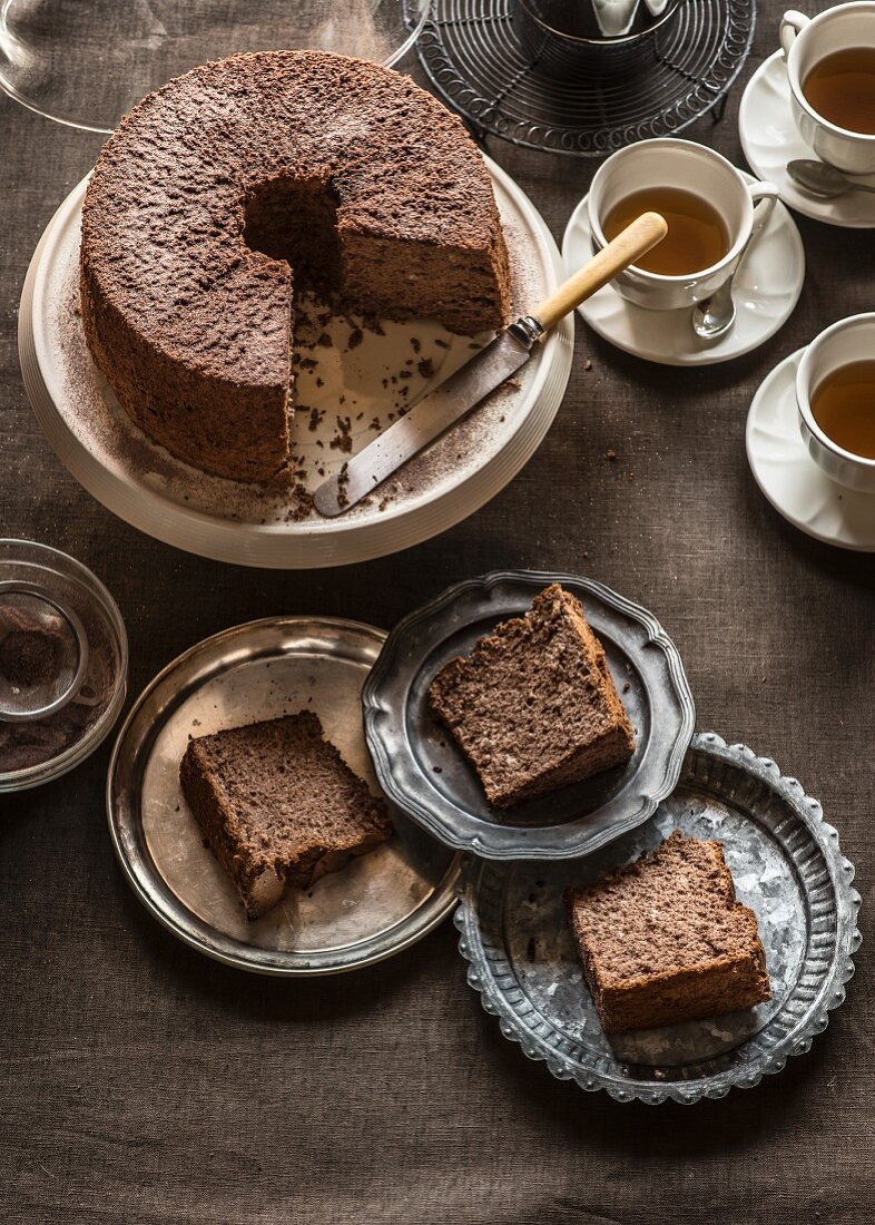 Schokoladenkuchen, in mehrere Stücke geschnitten, mit Teetassen
