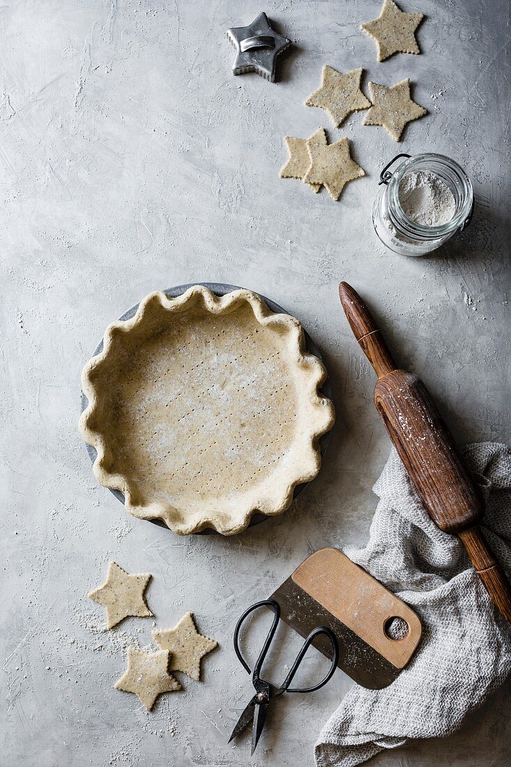 A pie tin being lined with shortcrust pastry