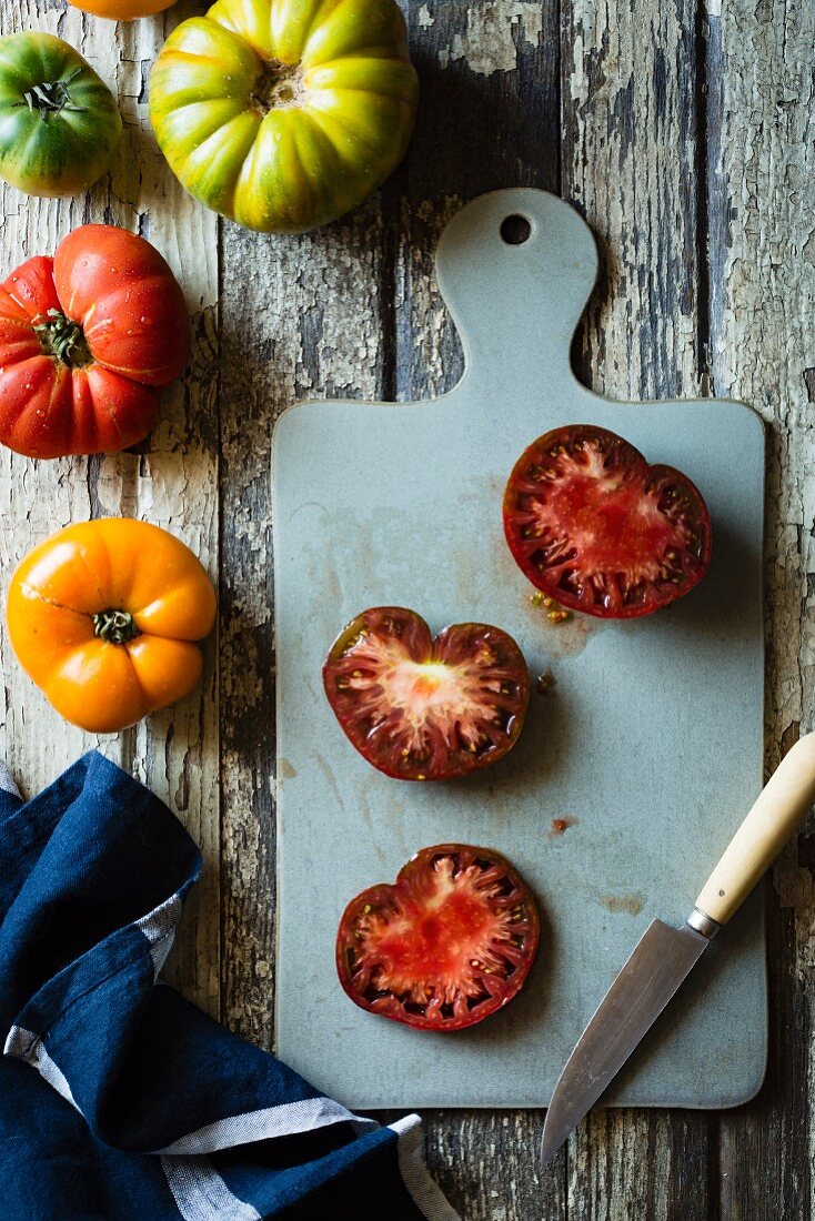 Different types of heirloom tomato, partially cut, on a chopping board