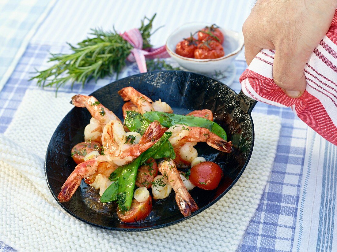Prawns in a pan with sugar snap peas and cherry tomatoes