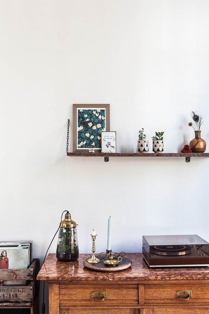 Ornaments on wall-mounted shelf above record player on sideboard