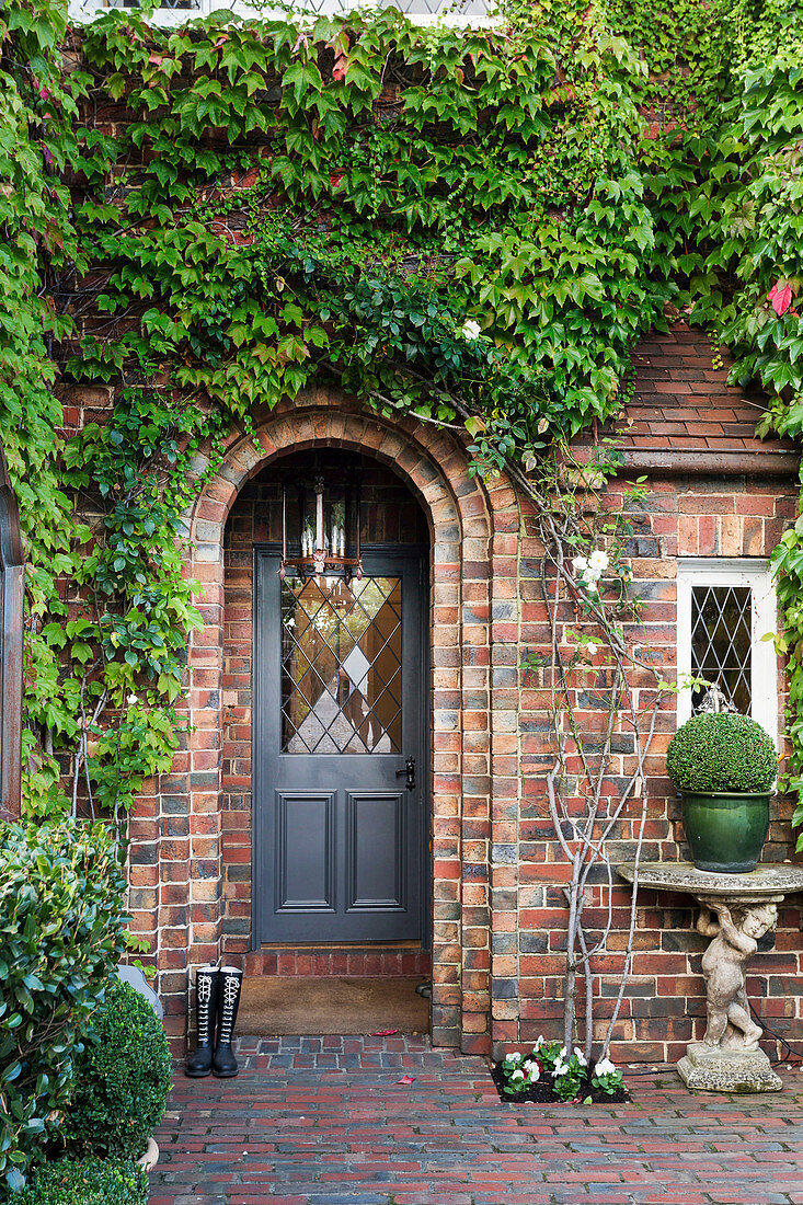 Brick facade with arches overgrown with wild wine