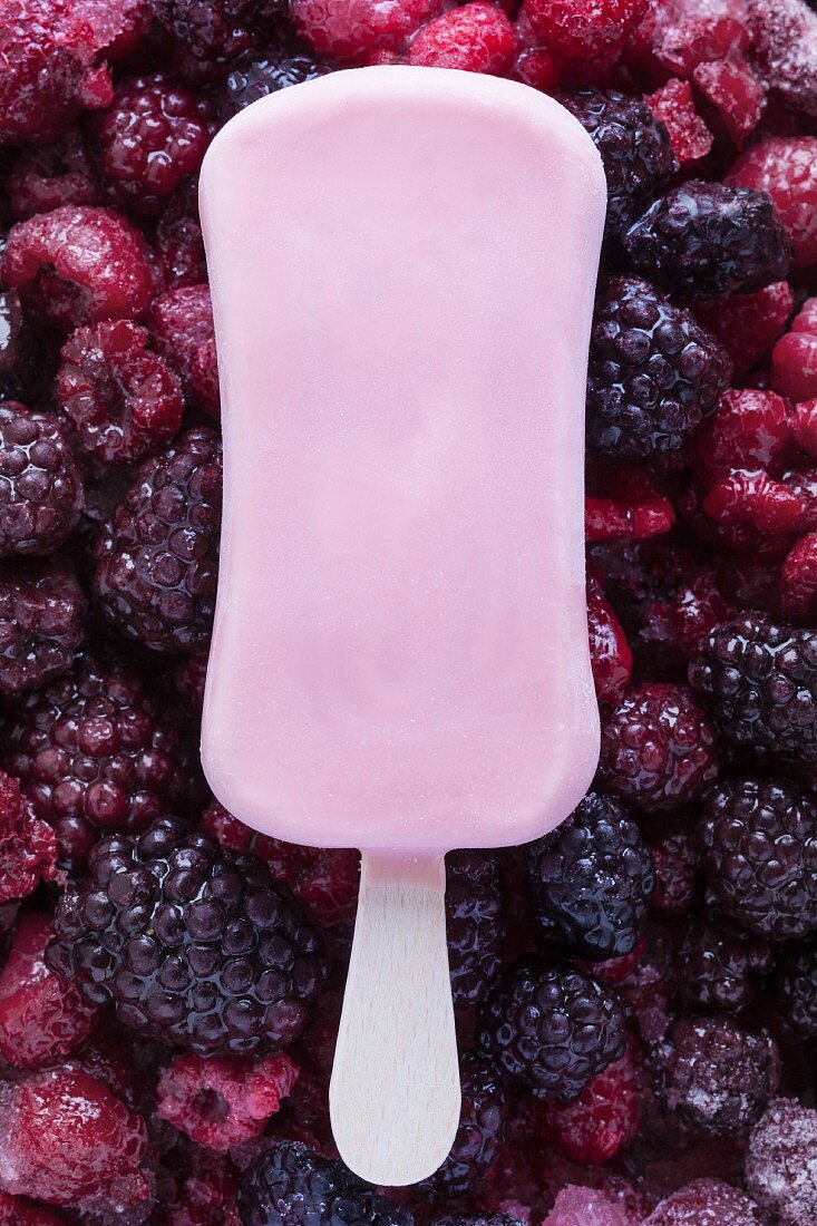 A raspberry ice lolly on frozen berries