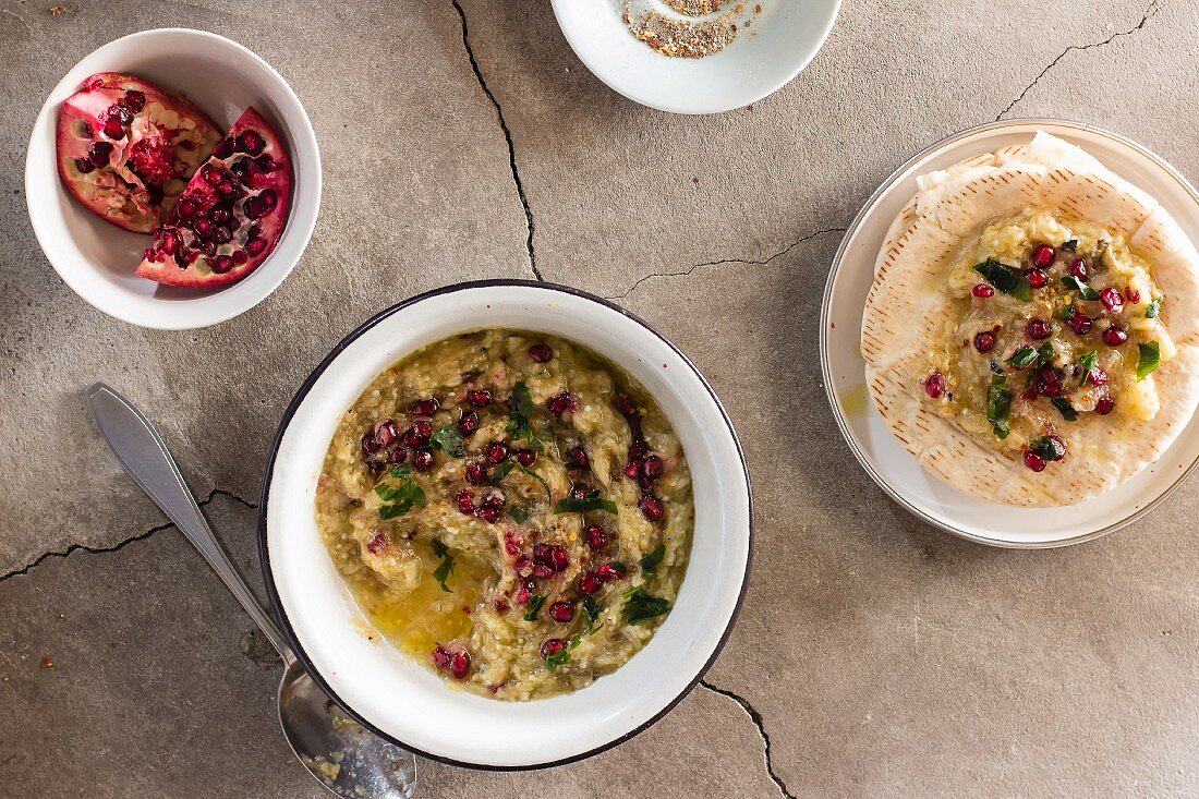 Baba ghanoush (aubergine dip) with pomegranate seeds, parsley, olive oil and pita bread