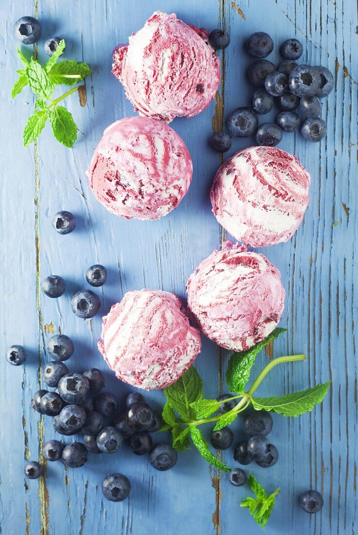 Blueberry ice cream and fresh blueberries on a blue background
