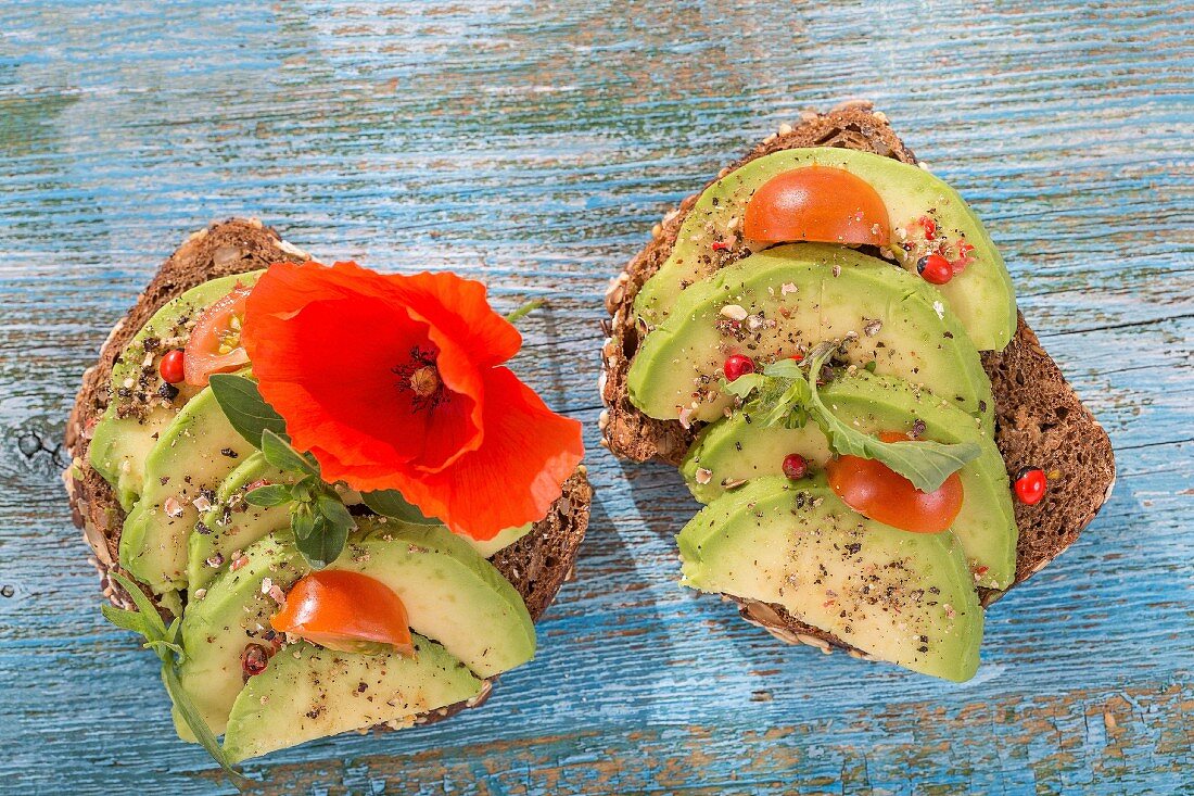 Wholegrain bread topped with avocado slices, tomato and a poppy