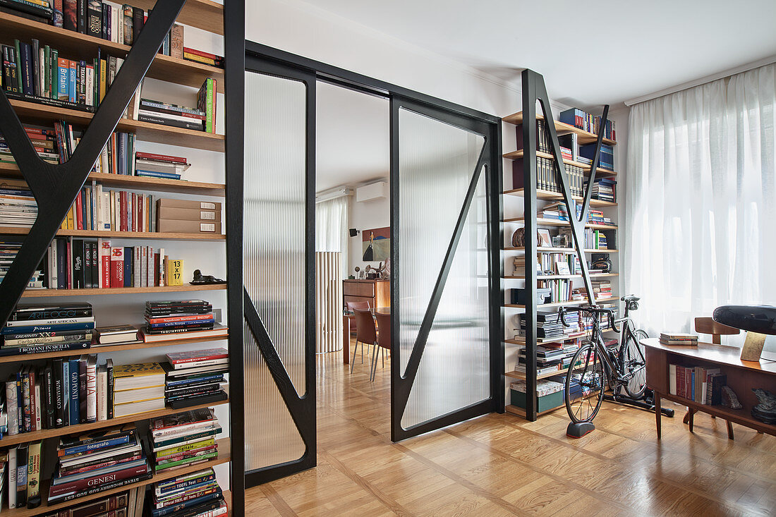 Floor-to-ceiling bookshelves, glass sliding doors and bicycle in front of window in study