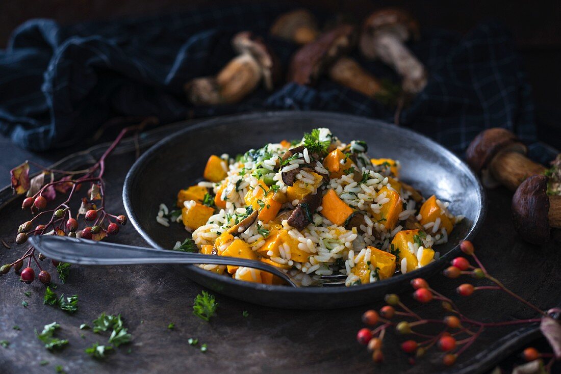 Vegan rice dish in a pan with pumpkin and wild mushrooms