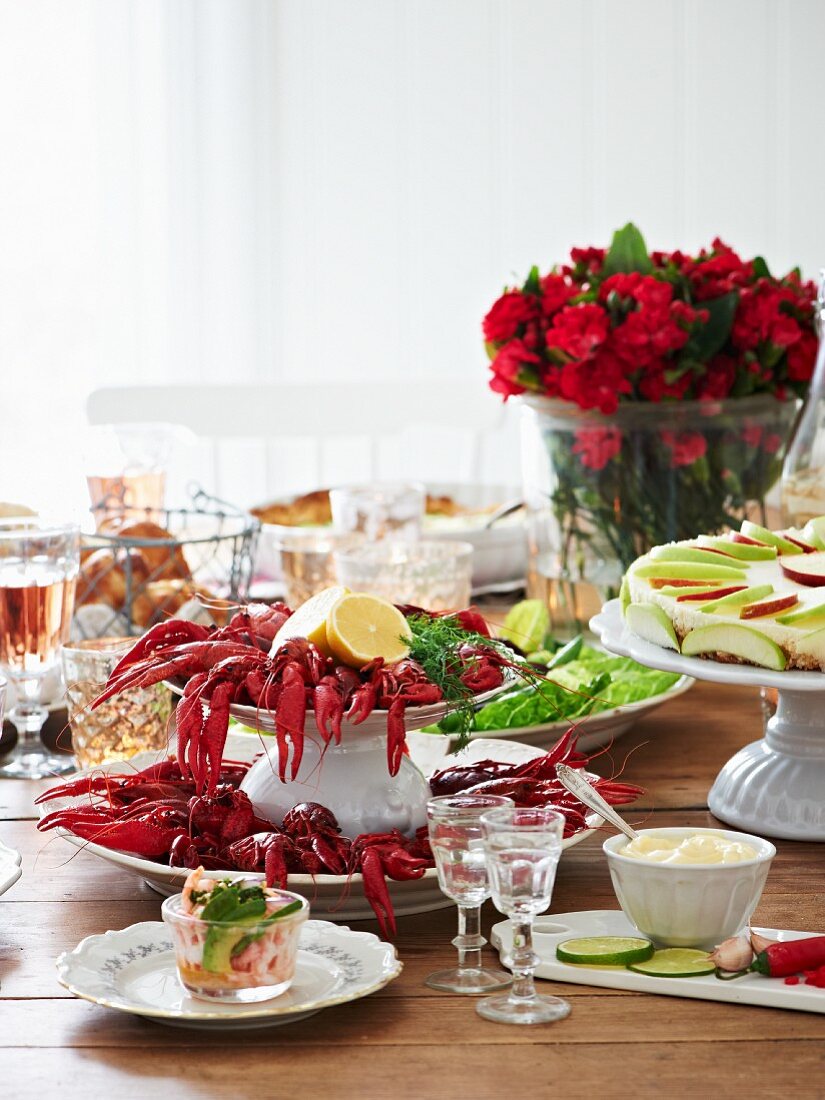 Gedeckter Tisch mit Flusskrebsen, Croissants, Apfeltorte, Mayonnaise und Meerrettichschnaps (Schweden)