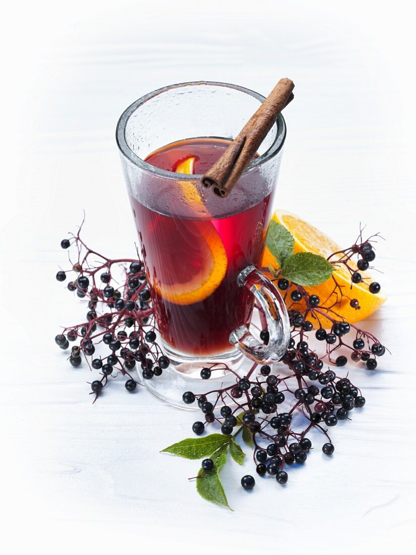 A glass of fruit tea with orange and a cinnamon stick