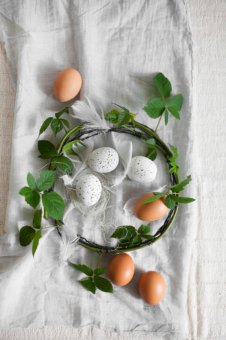Braune und weiße, gesprenkelte Eier und Kranz aus Brombeer-Ranken