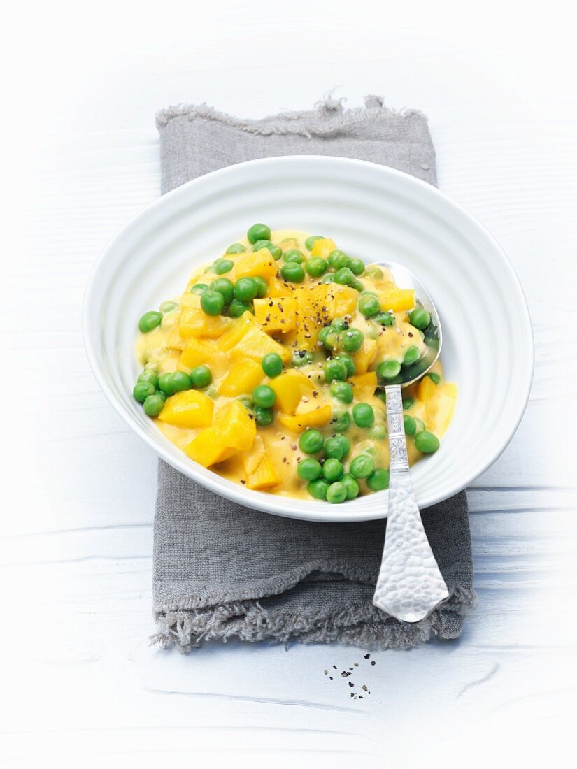 Golden yellow potatoes with peas in sauce