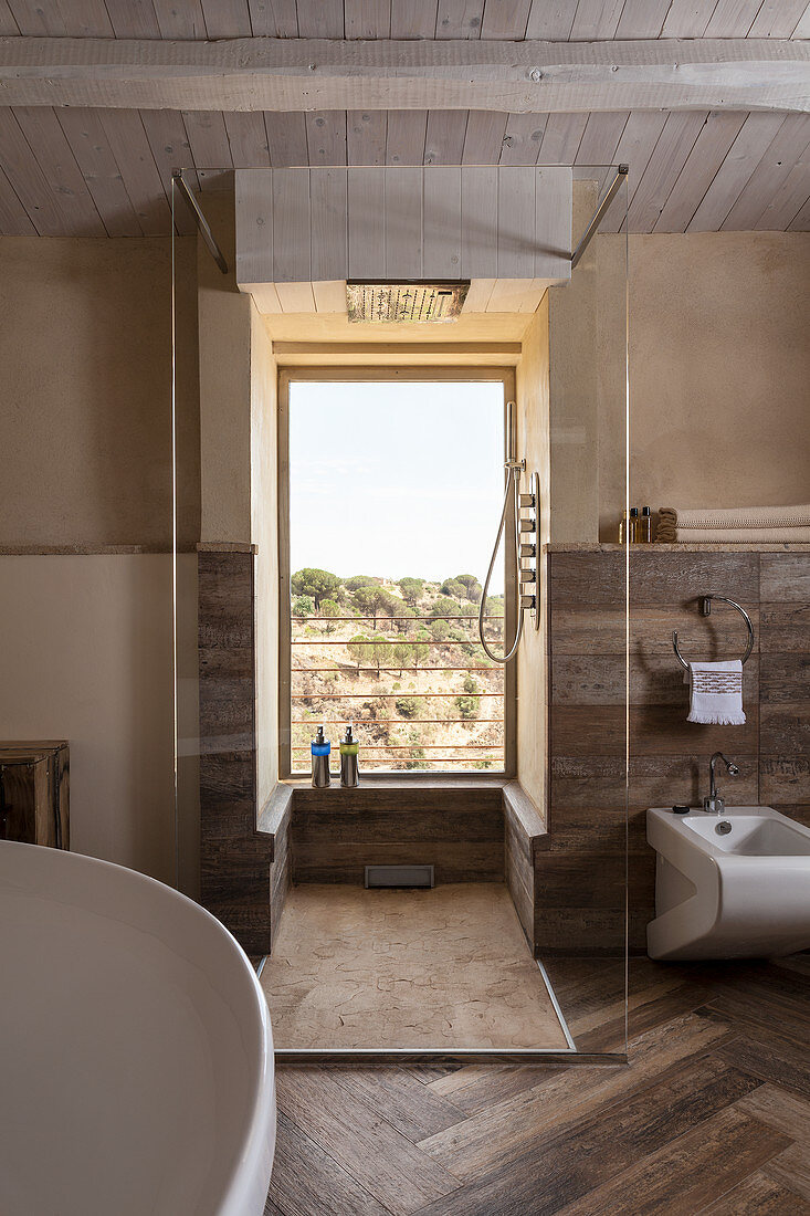 Shower area with view of countryside in bathroom with walls clad in reclaimed wood