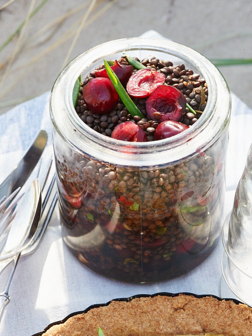 Black lentil salad with cherries in a glass jar