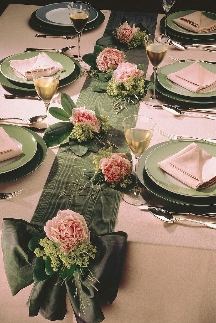 Festtafel mit grüner Schleife & rosa Blüten dekoriert