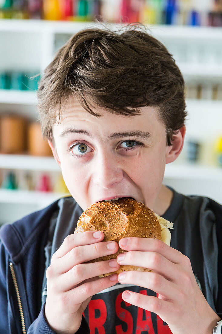 Teenage boy biting into a hamburger