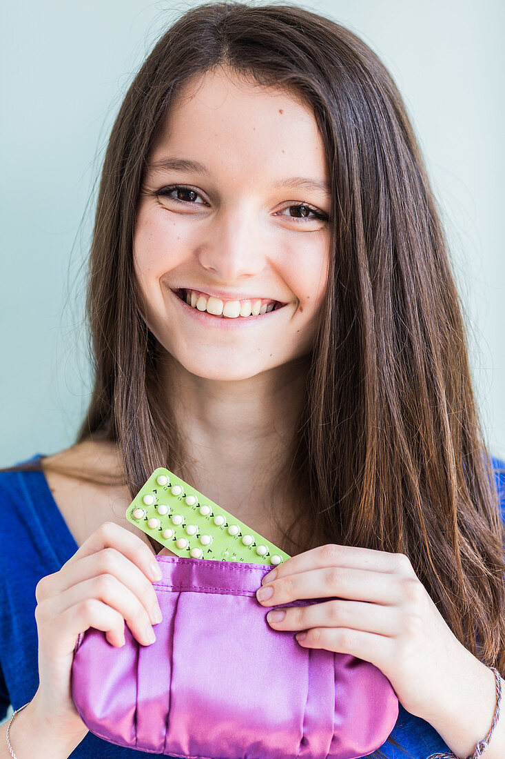 Teenage girl holding oral contraception pills