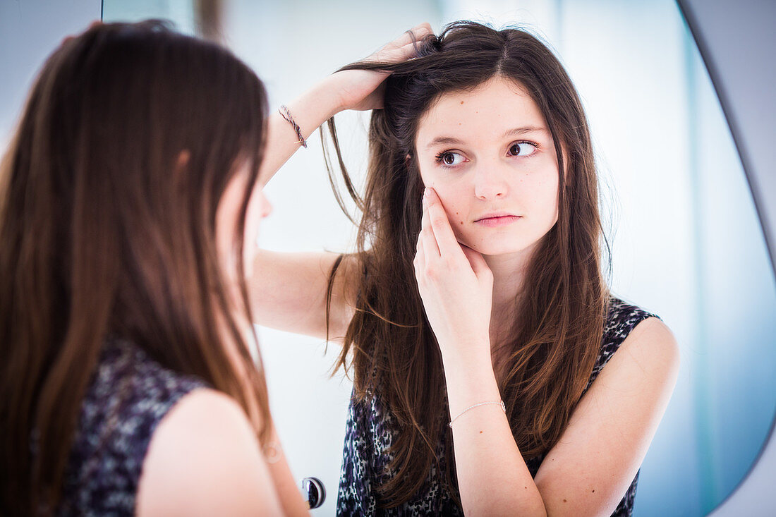 Teenage girl checking her face in the mirror