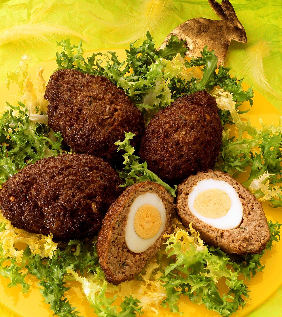 Mince frikadellas stuffed with eggs on endive salad