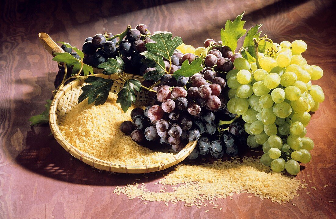 Still life with white & red wine grapes & a bowl of rice