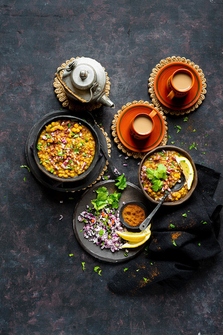 Veganes Linsencurry serviert mit gehackten Zwiebeln und Chai (Indien)