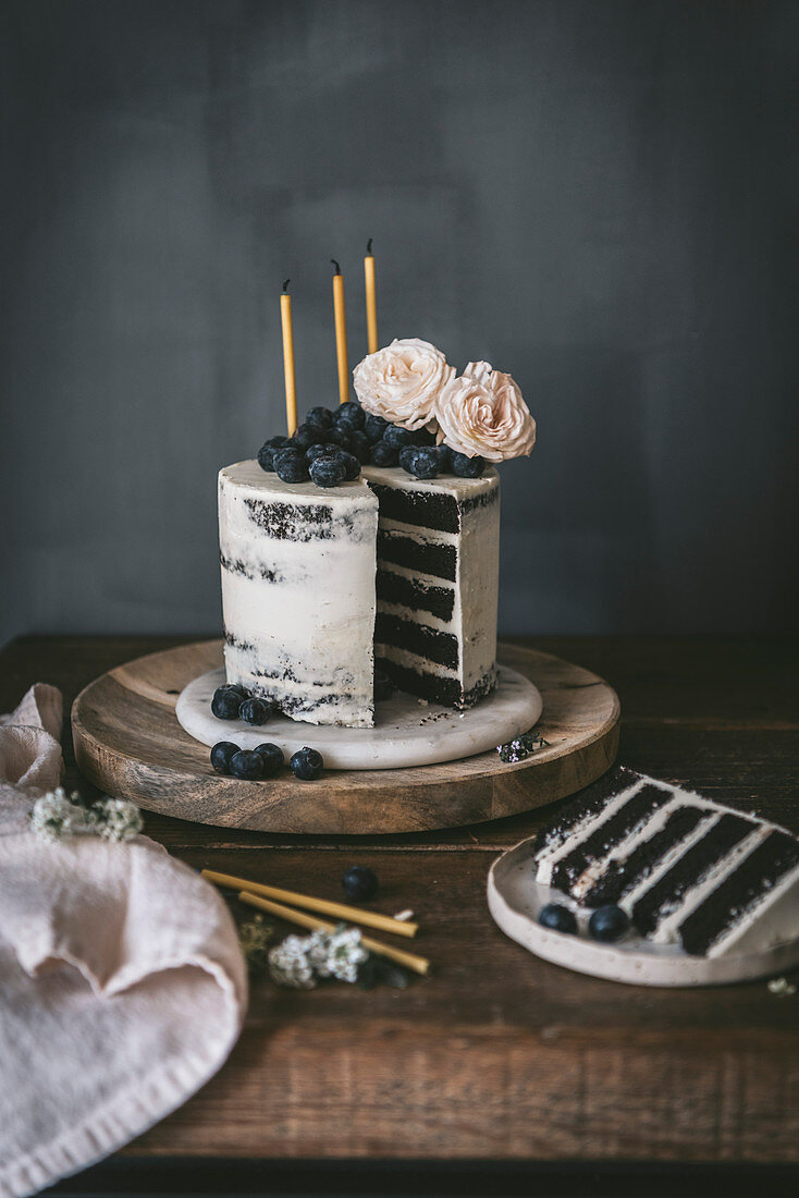 Schokoladen-Geburtstagstorte mit Vanillecreme, Blaubeeren und Kerzen