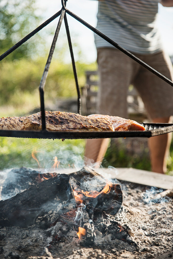 Spareribs on a grill grate over a campfire